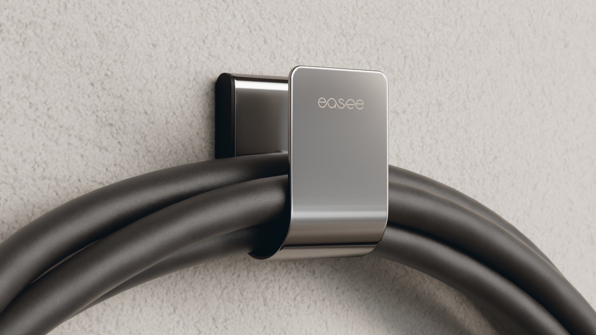 Easee U-Hook in chrome holding looped black EV charging cable on textured plaster wall, wall-mounted cable storage